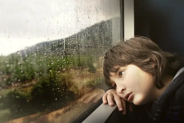 boy looking out window when raining
